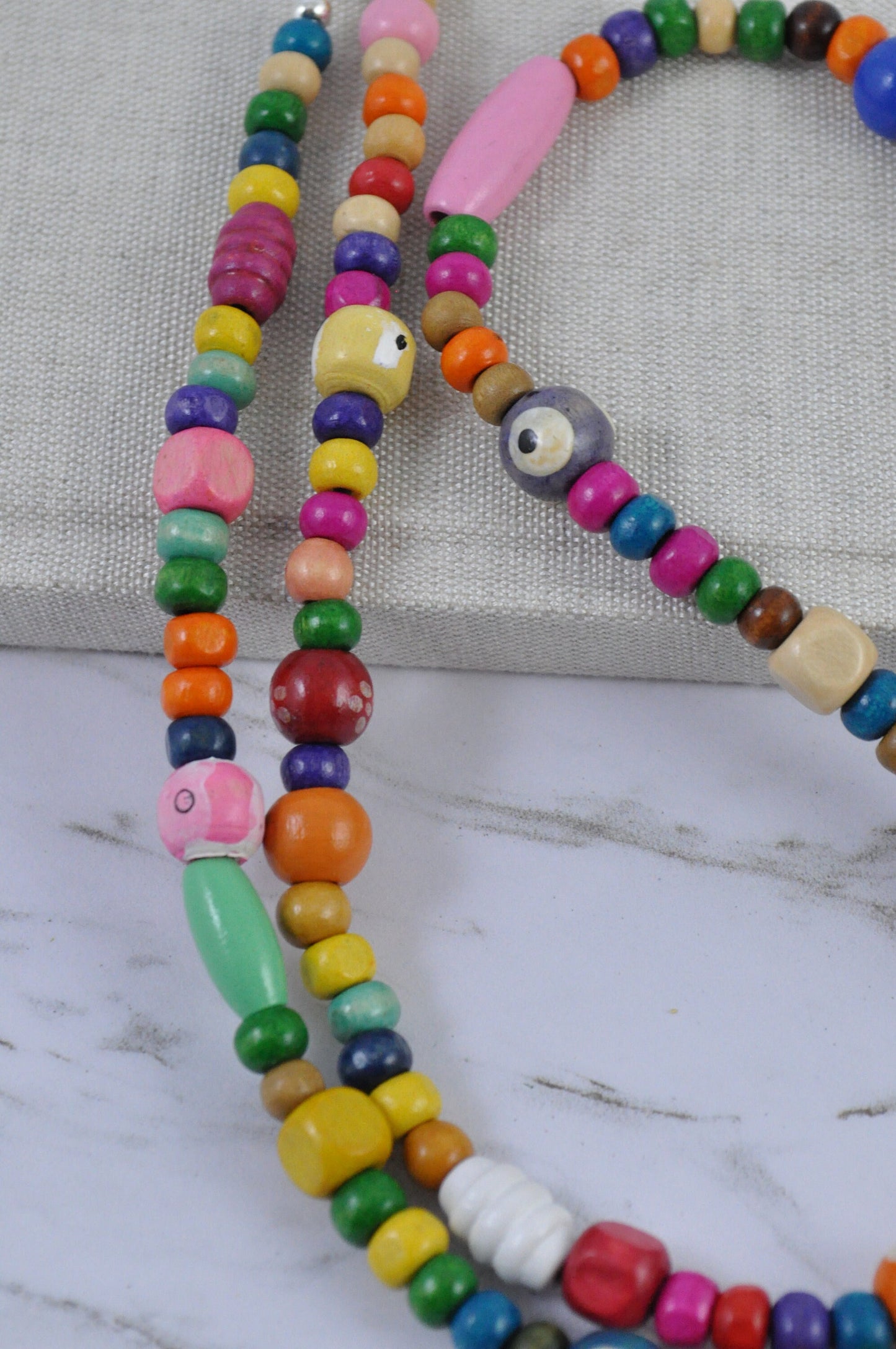 On a grey background, a close-up picture focuses on a section of the Wooden Beaded Sunglasses Chain, showcasing the detailed texture and finish of the wooden beads.