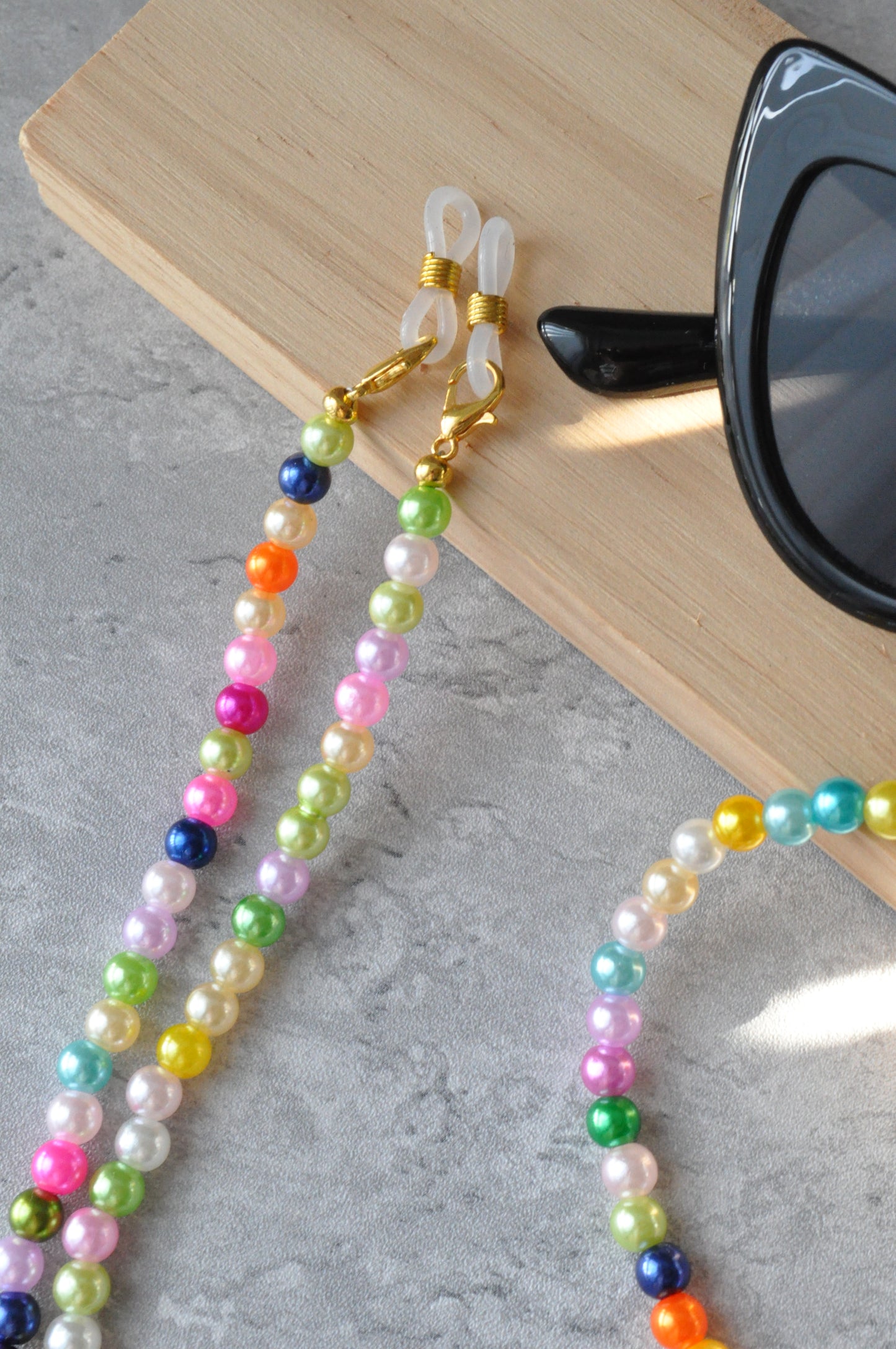 Close-up of the Rainbow Colourful Beaded Glasses Chain, highlighting the gold clasps against a grey background.