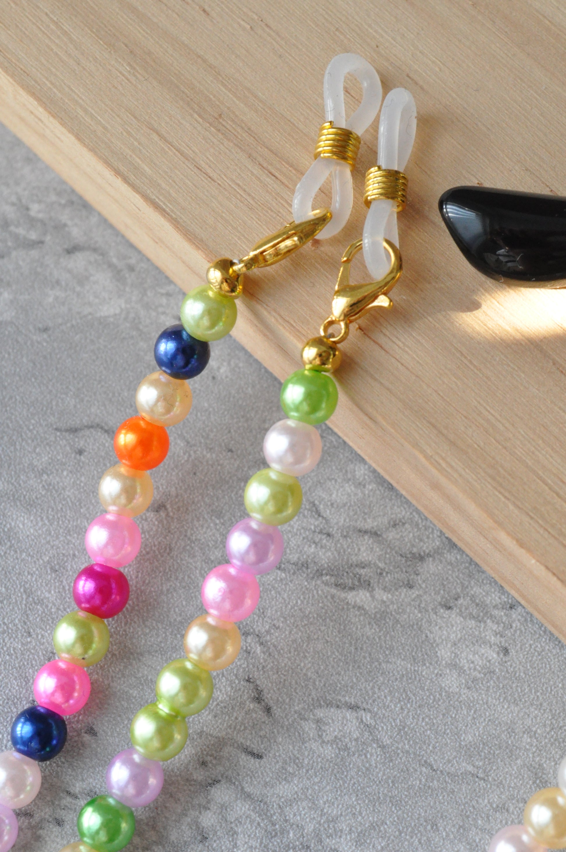 Close-up of the Rainbow Colourful Beaded Glasses Chain, highlighting the gold clasps on the wooden piece.