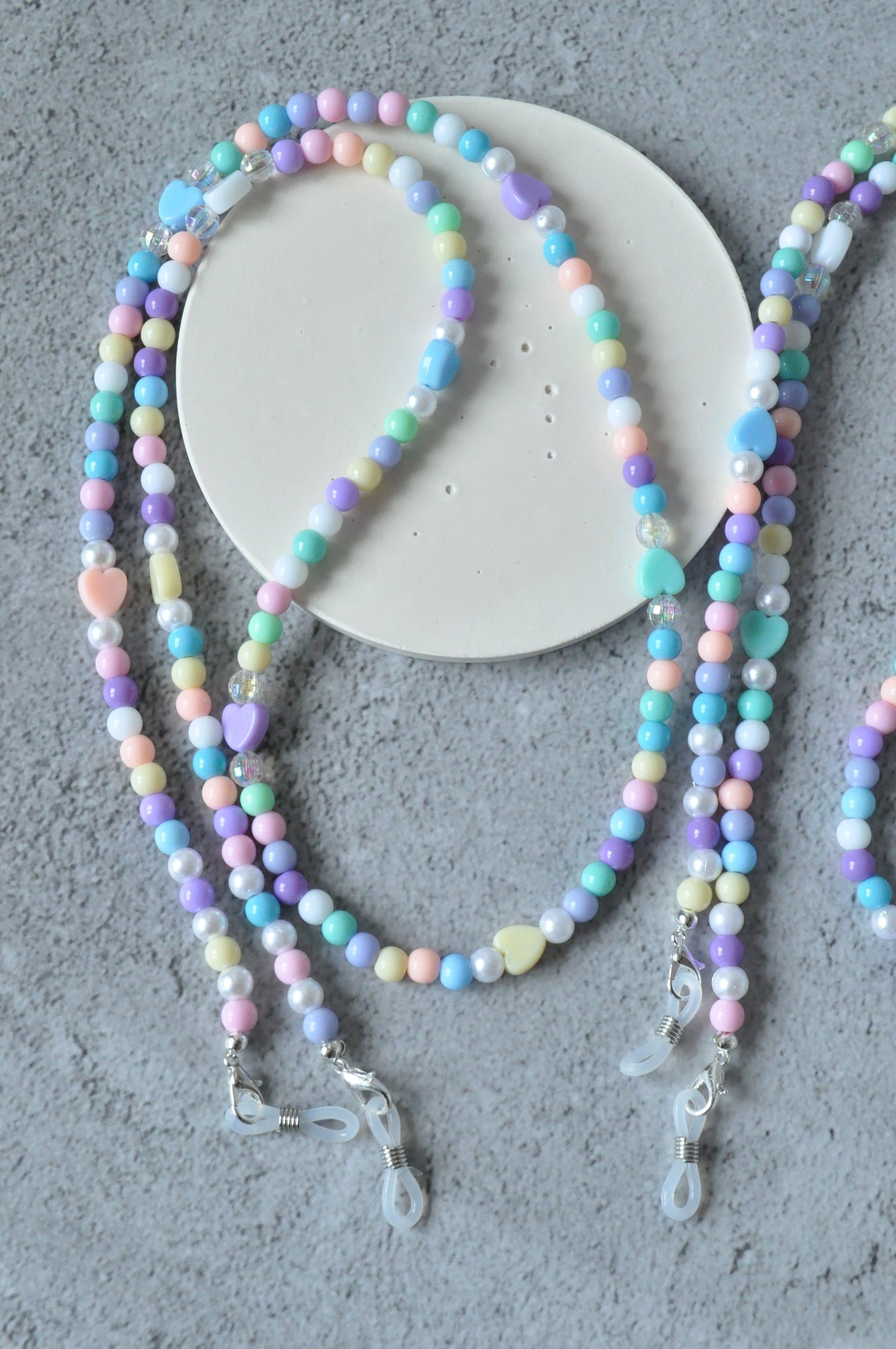 On a grey background, the full Cute Pastel Beaded Glasses Chain is displayed, featuring silver-plated clasps. The chain showcases its pastel beads and the elegant clasps in a complete view.